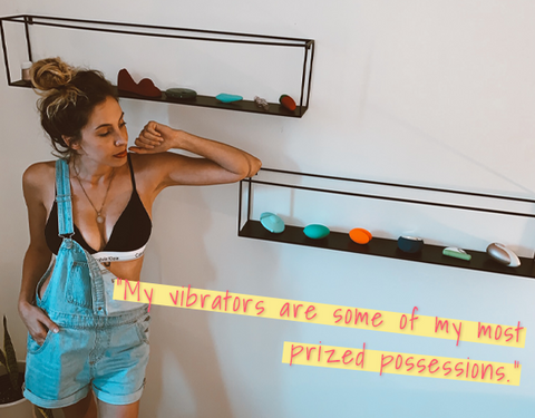 Photo of Lara Parker standing next to her wall of vibrators 